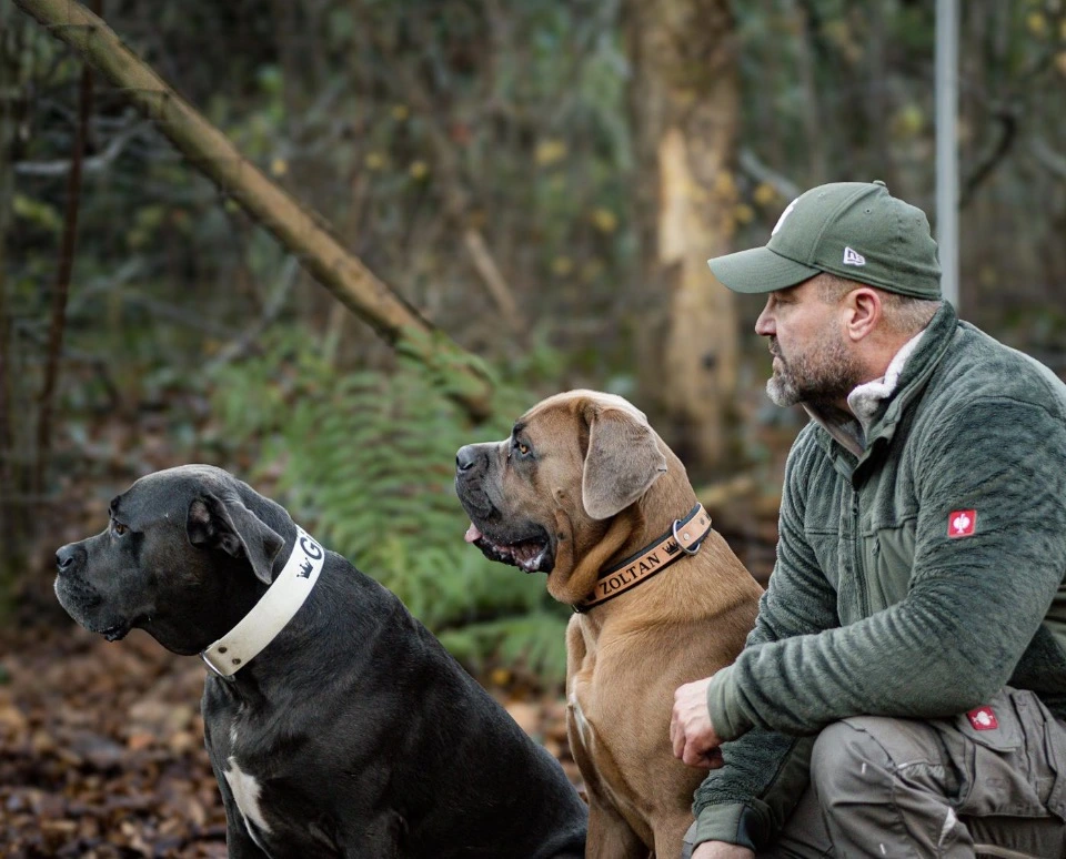 Mike Kasper seitlich mit zwei Hunden im Wald